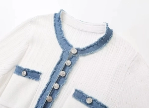 Detail of white rib-knit cardigan with frayed denim trim and silver anchor buttons