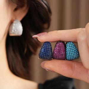 Close-up of geometric C-shaped earrings with colorful pavé zircons in four vibrant tones