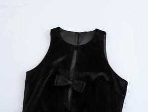 Detalle de vestido de terciopelo negro con lazo decorativo y abertura frontal de diseño