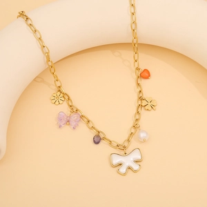 Detail of gold chain necklace with white enamel bow and colorful pendant charms