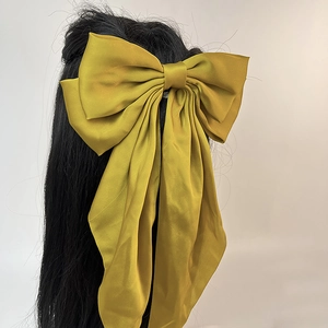 Détail d'une grande barrette à cheveux élégante en satin avec nœud et rubans vert olive