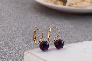 Macro shot of gold titanium leverback earrings with purple faceted crystal beads