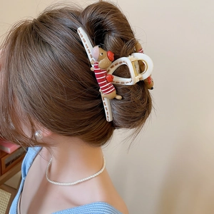 Detail showing a white star-shaped hair claw clip with a cute striped dog charm