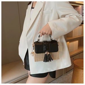 Detail of a chic straw and black leather crossbody bag featuring a tassel and rope strap