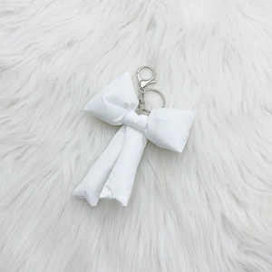 Detailed macro view of white satin ribbon bow keychain with silver metal lobster clasp