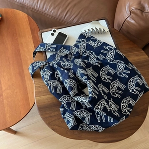 Close-up of a navy canvas tote bag with white animal patterns on a wooden table