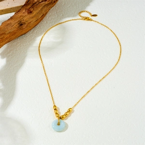 Close-up of golden choker with light blue ring pendant and gold beads on white background