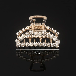 Detail view of a 5cm golden alloy hair claw clip with sparkling rhinestones and reflection
