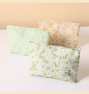 Close-up of floral embroidery detail and premium linen fabric on a makeup pouch