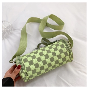 Detail of green checkerboard cylinder bag with pleated texture and wide webbing strap