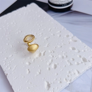 Close-up of 18K gold ring with one zircon stone and one matte texture oval end