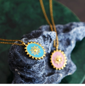 Macro detail of oval sunburst enamel pendants in blue and pink on 18K gold plated chains