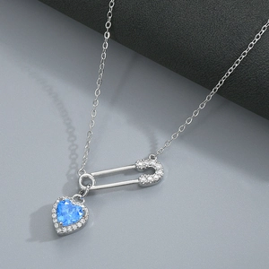 Detailed macro view of heart-shaped blue zircon pendant with diamond-set safety pin chain