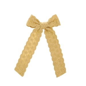 Detail of yellow lace crochet hair bow featuring hollow floral pattern and scalloped edges