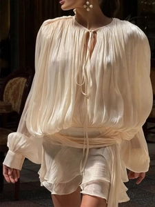 Detailed view of champagne pleated chiffon dress with ruffled layers and tie-neck design