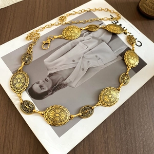 Detailed view of vintage gold textured oval chain belt on fashion magazine