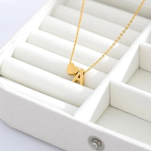 Close-up detail of the personalized gold necklace with heart and letter A pendants