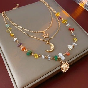 Detail of multilayer gold necklace featuring sun moon star pendants and colorful beads