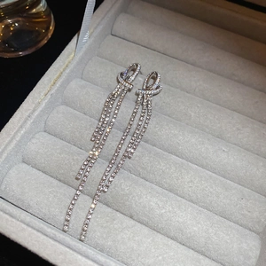 Macro detail of silver tassel earrings with pavé rhinestones in a gray velvet box