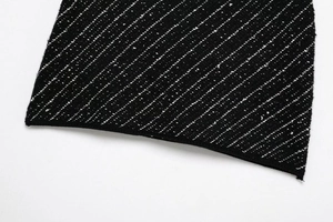 Detailed close-up of black knit fabric with white polka dot twill texture and trim