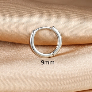 Close-up of 9mm minimalist silver hoop earring on champagne silk background