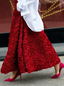 Detail of vibrant red long skirt with 3D floral petals and tiered texture design