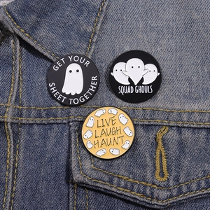 Three spooky Halloween ghost enamel pins styled on a blue denim jacket pocket