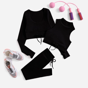 Flat lay of black 3-piece yoga set with ribbed texture, drawstring detail and fitness gear
