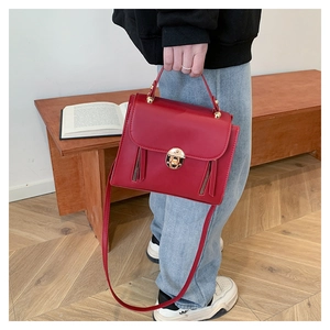 Detail of red briefcase bag showing golden round rotary lock and vertical zippers