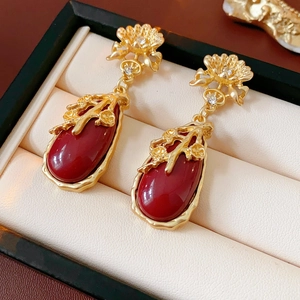Close-up of vintage gold floral earrings with red gemstone droplets and diamond accents