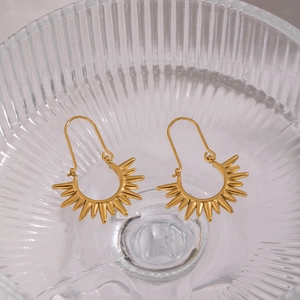 Golden bohemian sunburst hoop earrings made of stainless steel displayed on a glass base