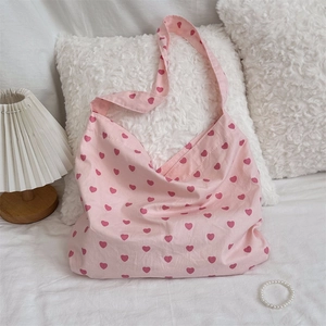 Detailed view of a pink canvas tote bag with red heart patterns on white bedding