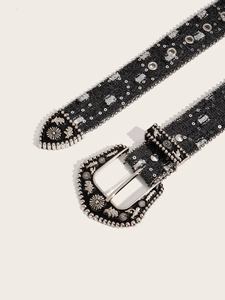 Close-up of black fabric belt featuring silver rivets and vintage engraved metal buckle