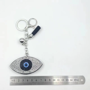 Evil eye rhinestone keychain with blue tassel measured against a ruler for scale