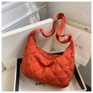 Detailed view of an orange quilted nylon crossbody bag featuring a wide shoulder strap