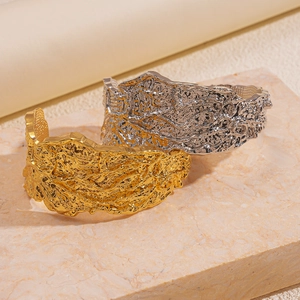 Adjustable wide open cuffs with irregular lava texture in gold and silver finishes