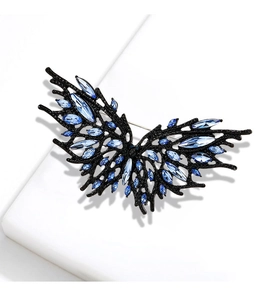 Detail of dark butterfly brooch with blue crystals on black metal branch wings