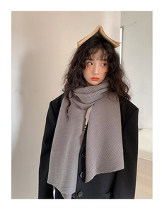 Detailed view of the vertical pleated texture on a long grey winter scarf