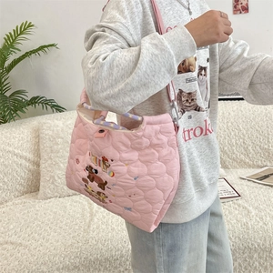 Detail of pink heart-quilted crossbody bag with puppy embroidery and purple handle