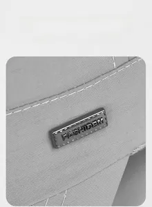 Macro shot of metal logo plate on grey quick-dry cap with white contrast stitching