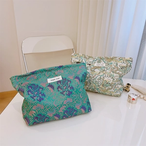 Detail of jacquard brocade makeup bags showing floral and dragon textures with logo tag