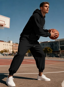 Tuta termica nera da uomo con cappuccio e pantaloni sportivi indossata all'aperto