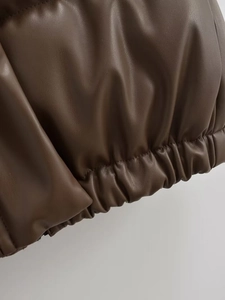 Macro detail of dark brown faux leather texture and elastic ribbed hem on the vest