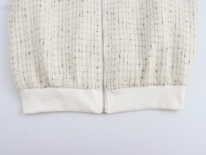 Détail de l'ourlet de la veste en tweed blanc avec fermeture éclair et poignets côtelés