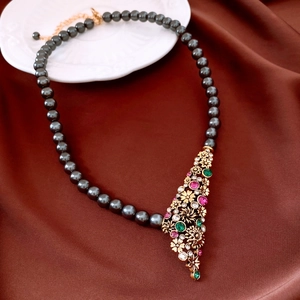 Dettaglio della collana vintage a fiore con perle grigio scuro su seta marrone
