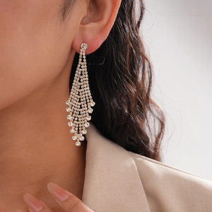 Detailed view of long gold tassel earrings with rows of sparkling diamond-like rhinestones