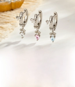 Detail view of bow heart earrings with clear, pink, and blue cubic zirconia stones