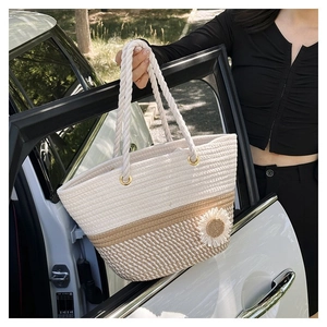 Detail of woven tote bag with white flower decoration and rope handles in outdoor setting