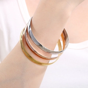 Close-up of three-color minimalist 8mm stainless steel bangles in gold, silver, and rose gold