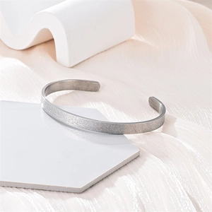 Primer plano de un brazalete de acero inoxidable plateado esmerilado con acabado brillante
